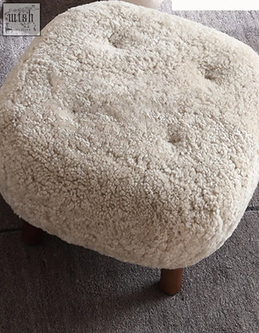 Cream-colored plush sheepskin ottoman with tufted detailing and wooden legs for fitz armchair lounge chair with artificial wool