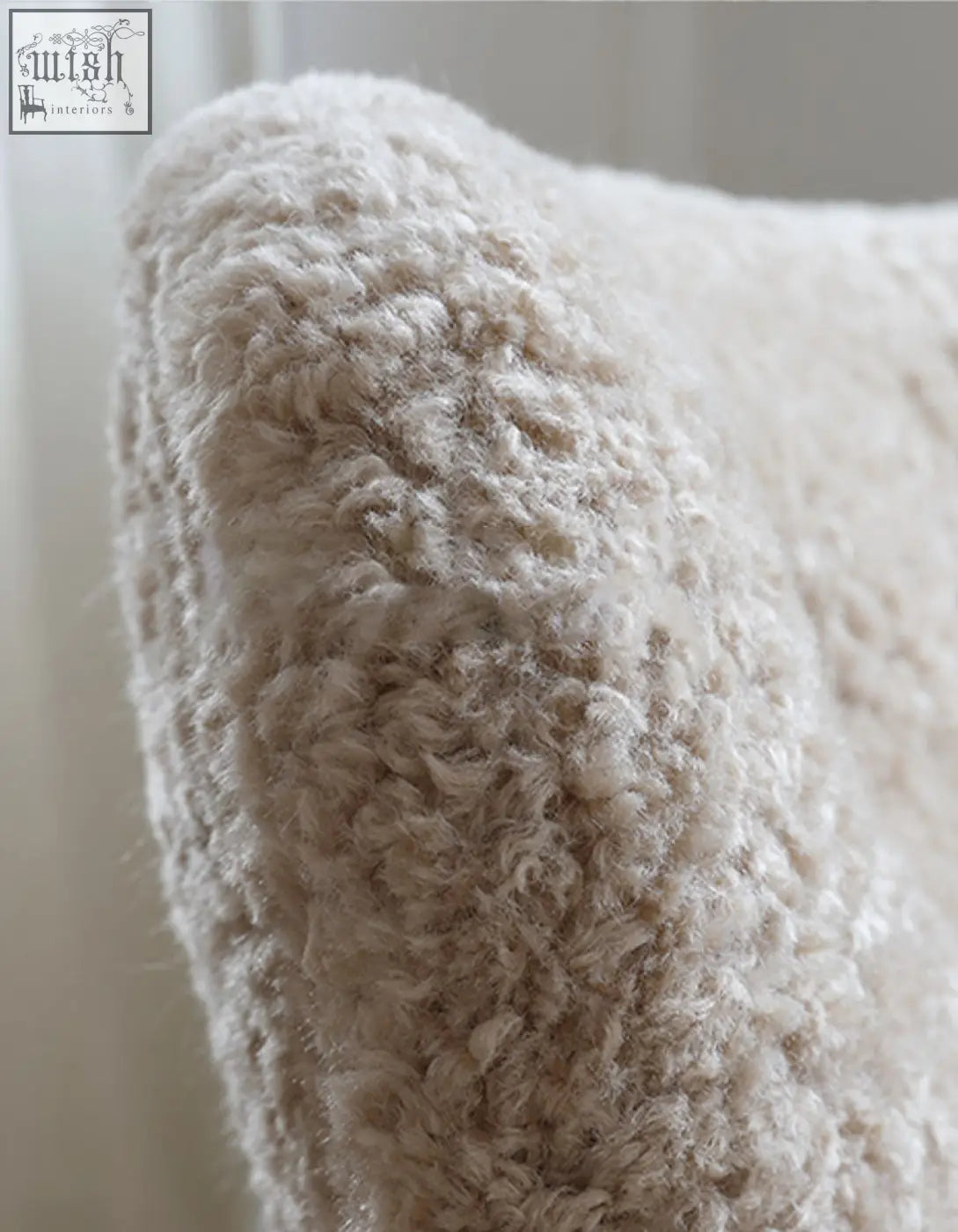Cream-colored plush pillow with soft curly artificial wool fiber on fitz armchair lounge chair seat