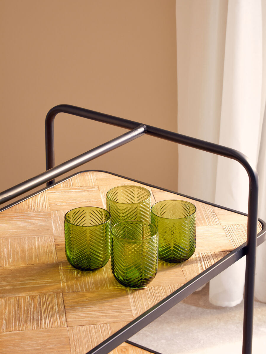 Four green tumblers from the fleur set feature olive-green glass with a chevron texture on a woven wooden tray