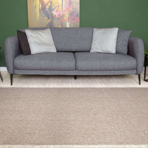 Gray textured fabric sofa with black legs and striped throw pillows on a flex beige low pile solid rug