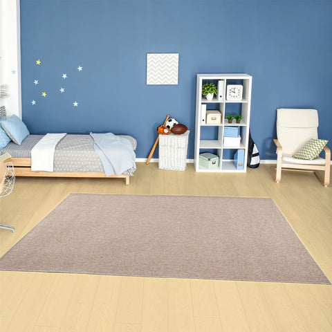 Beige low pile flex beige low area rug with subtle woven texture on light wood flooring