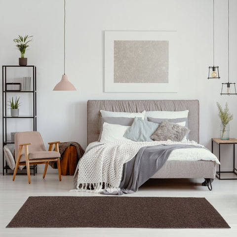 Gray upholstered bed with tufted headboard and layered bedding on flex brown low pile solid rug