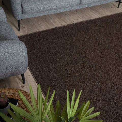 A plush flex brown low pile solid rug with a textured weave lays on a wooden floor perfect for cozy spaces