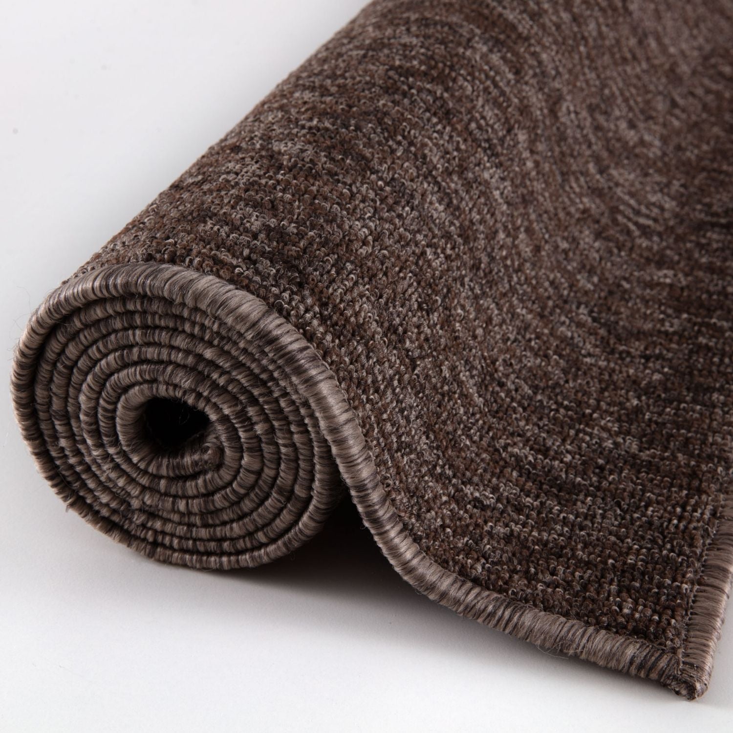 A rolled-up flex brown low pile solid rug with brown low pile plush woven texture and neatly finished edges