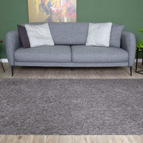 Gray low pile area rug with subtle heathered pattern and fringed edges in flex grey low style