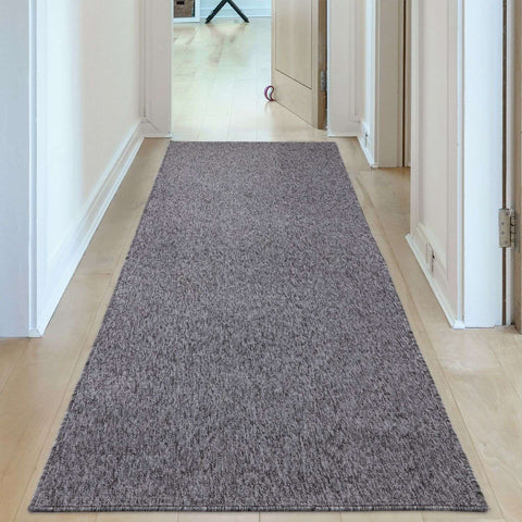 A textured grey low pile runner rug with a subtle heathered pattern laid out in a hallway flex grey low pile