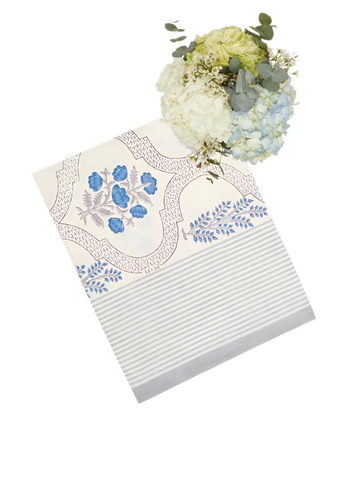 A cream-colored flora blue tablecloth table runner with delicate blue floral pattern and striped border
