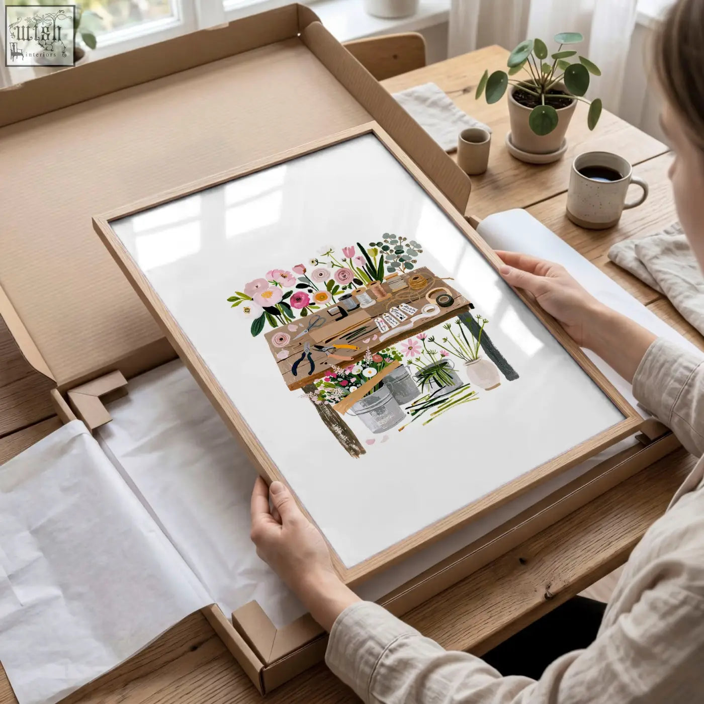 A framed botanical illustrated print featuring a wooden workbench with pink peach and green flowers for country cottage floral art