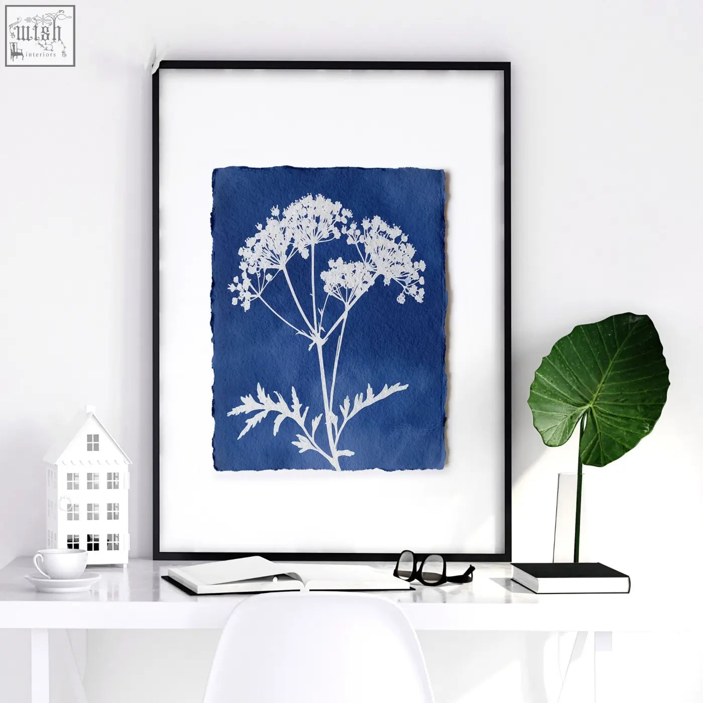 A framed floral art wall print with white cyanotype wildflowers on deep blue paper in a sleek black frame