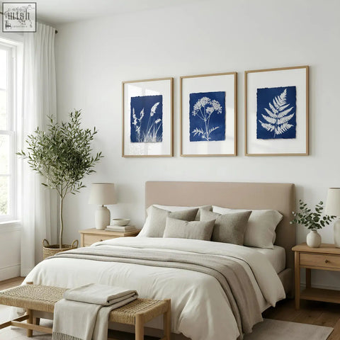Three framed floral art wall prints with white wildflower silhouettes on indigo cyanotype backgrounds in wood frames