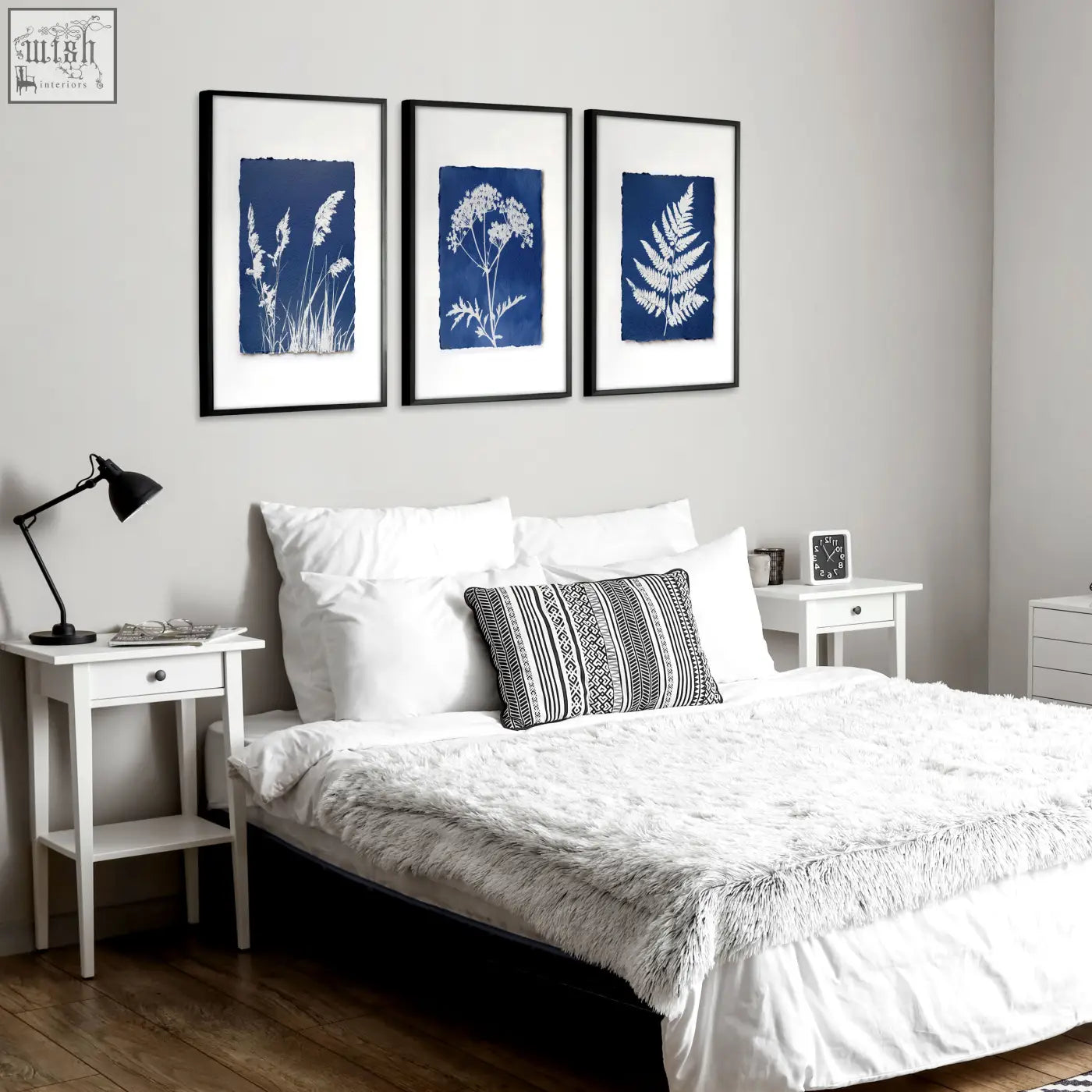 Three framed floral art wall prints with white plant silhouettes on deep blue cyanotype background in black frames