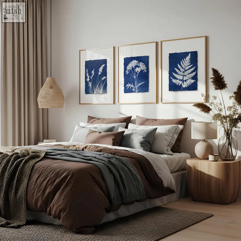 Three framed floral art wall prints featuring white plant silhouettes on deep indigo cyanotype paper in light wood frames