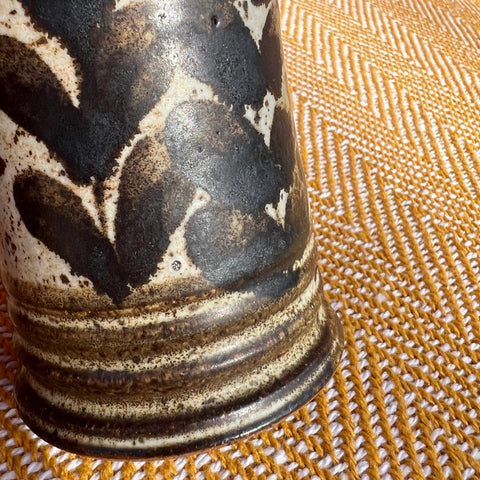 A floral ceramic vase with a glossy black and cream marbled glaze and subtle ridges near the base