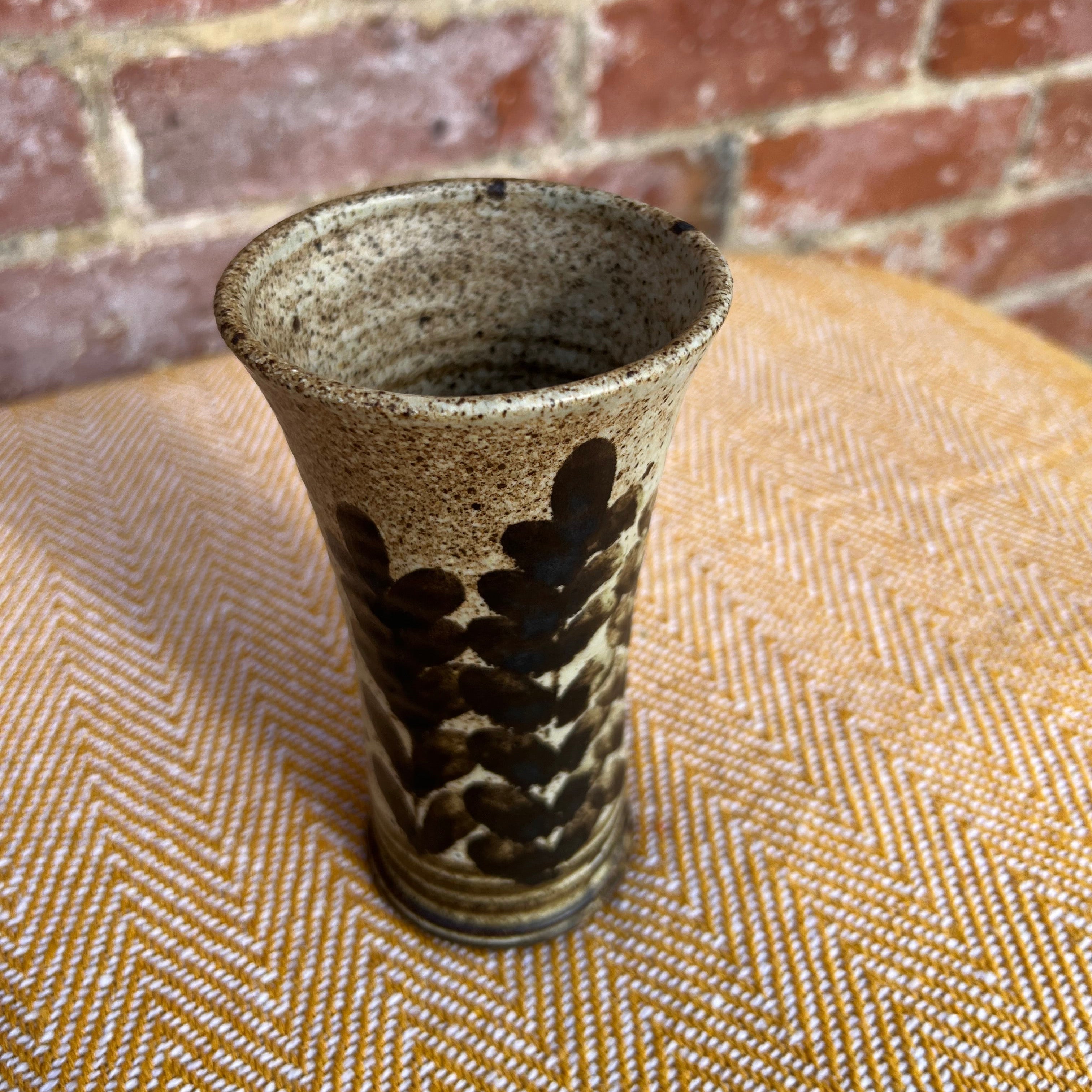 A rustic floral ceramic vase with speckled beige glaze and dark brown leaf patterns for home decor