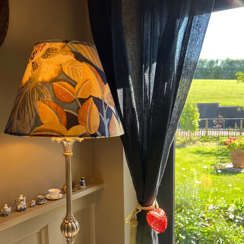 A handmade floral midnight velvet empire lampshade with vibrant autumn leaf pattern on ornate metallic stand