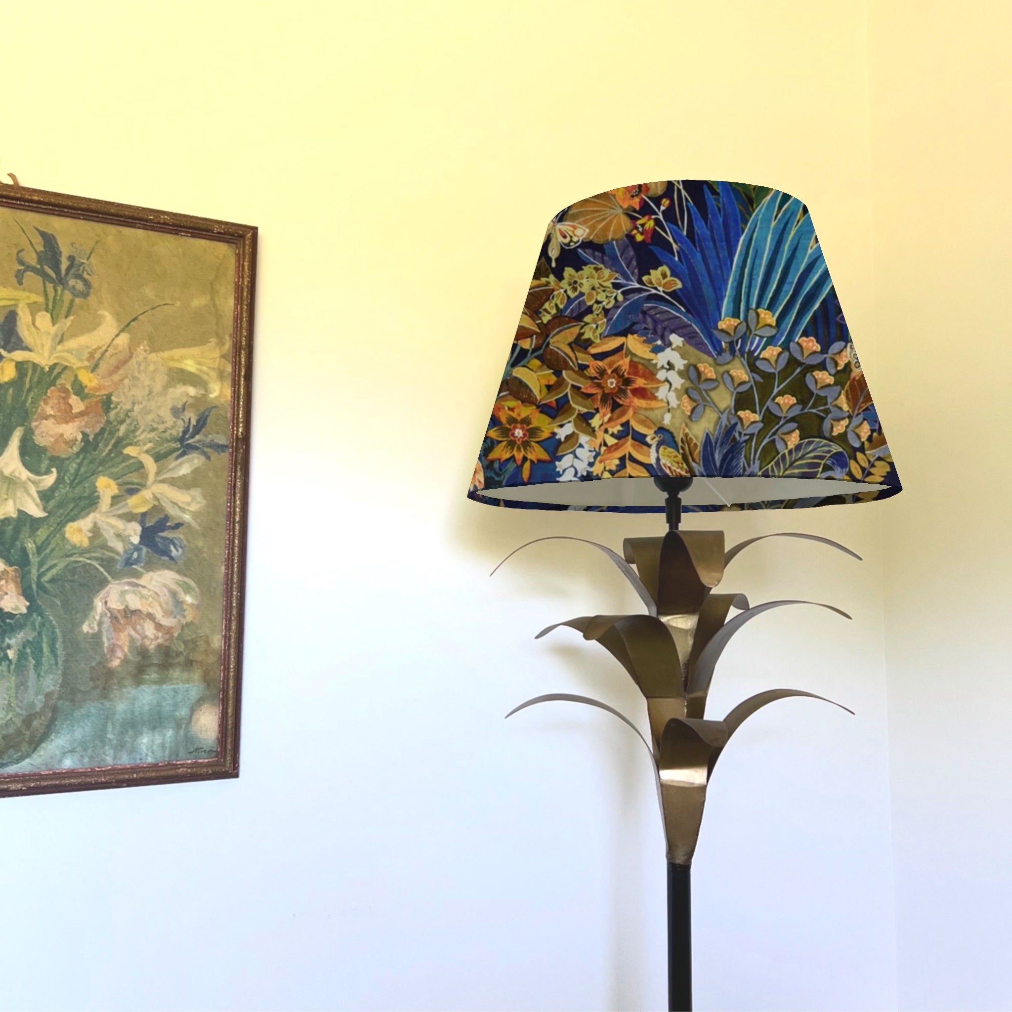 A floral midnight velvet handmade lampshade with deep blue gold floral patterns on a metallic palm leaf lamp base