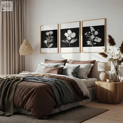 A minimalist bedroom with floral wall art featuring a set of 3 charcoal and white botanical prints above the bed