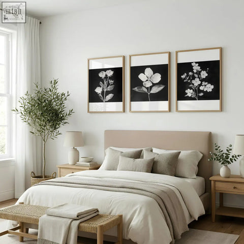 Beige upholstered bed with matching pillows and neutral throw next to charcoal and white floral wall art set of 3