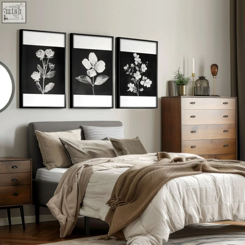 Three framed black and white floral wall art prints with white borders hanging above a bed in a set of 3