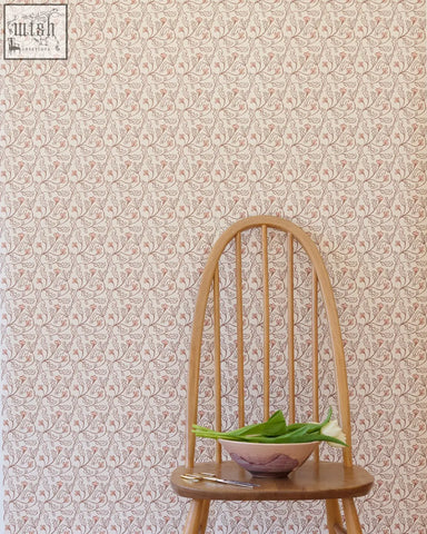 A light wood chair with curved back and vertical spindles holding a bowl of green leaves against florence wallpaper shell small repeat