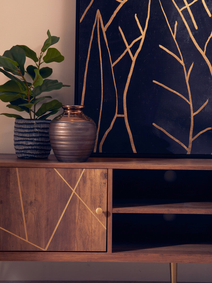 A metallic ribbed ceramic vase with copper rim on a wooden console table in the flori media unit setup