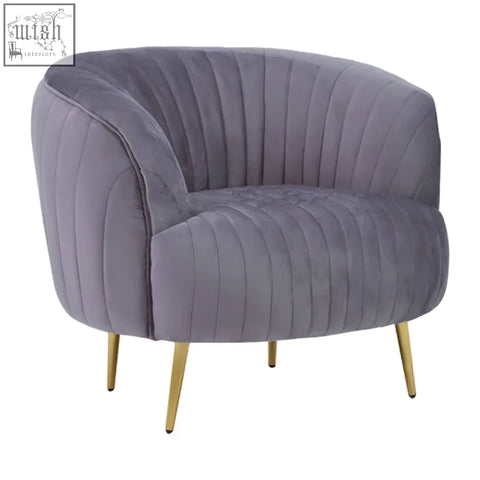 A plush florina grey velvet chair with vertical pleats and slender gold legs perfect for cozy seating