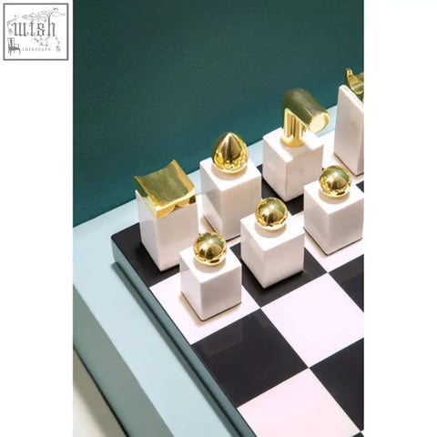 White ceramic chess pieces with polished gold tops on a black and white board in flos marble and wood chess set
