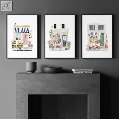 Three framed watercolor flower art wall prints featuring charming flower shop facades in pink blue and white