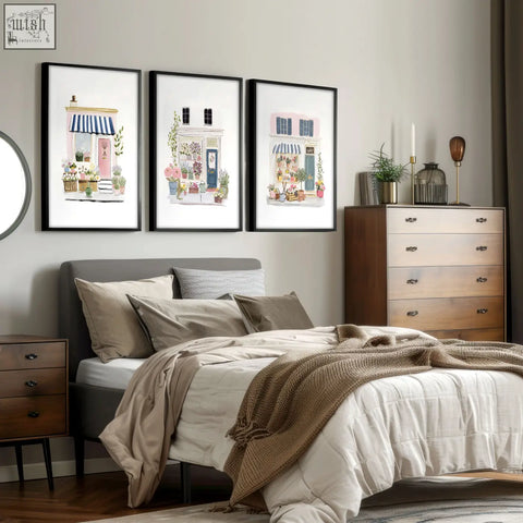 Three framed flower art prints of charming blue pink and white flower shop facades hang above the bed
