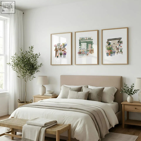 Three framed flower print botanical illustrations in light wood frames hang above the bed as flower shop wall art