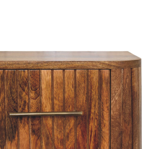 A rustic wooden fluted bedside table with vertical slats and a brass handle for bedroom storage