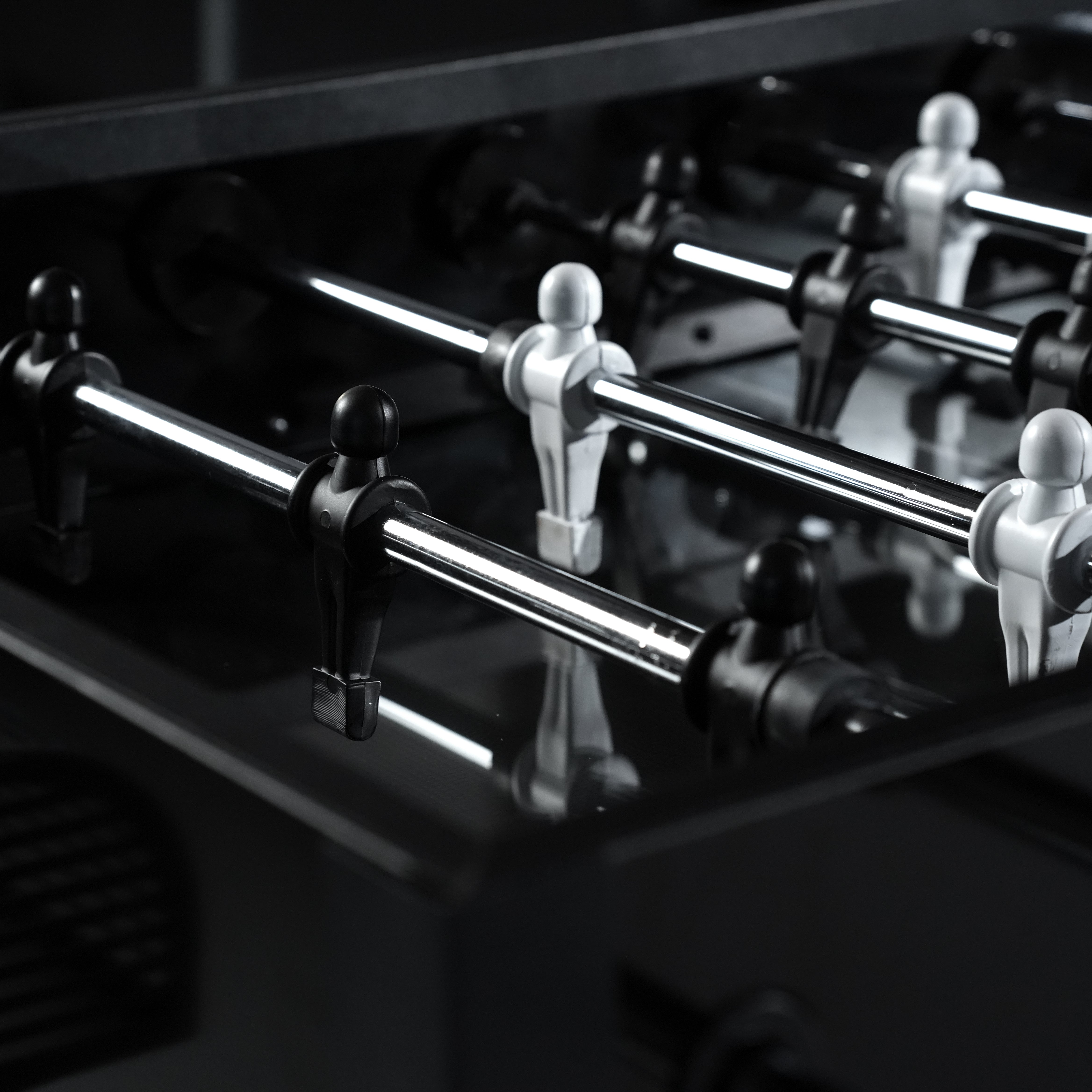 Shiny chrome-plated foosball player figures mounted on black rods for a sleek foosball table setup