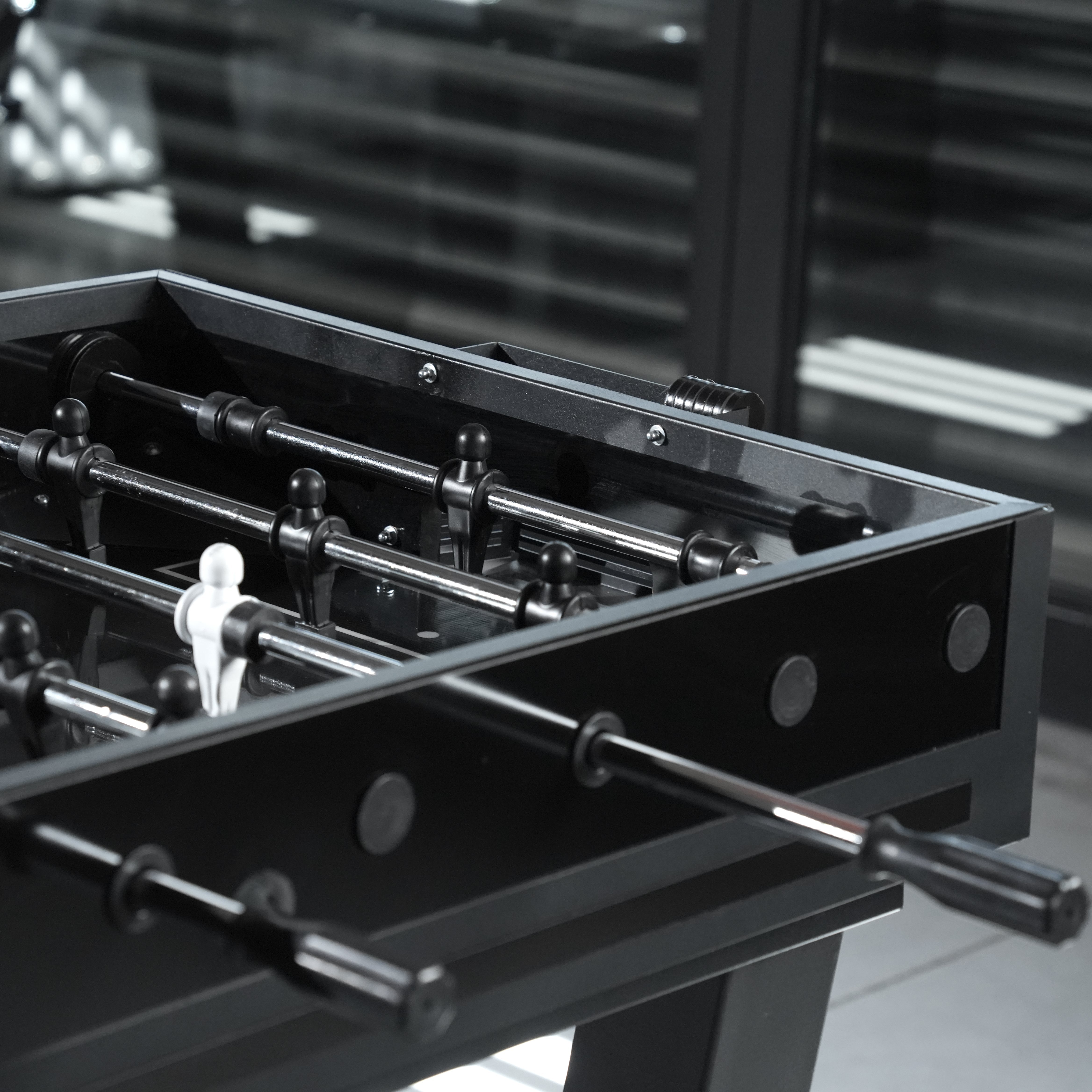 Black foosball table with sleek glossy finish and chrome rods featuring white player figures for fun play