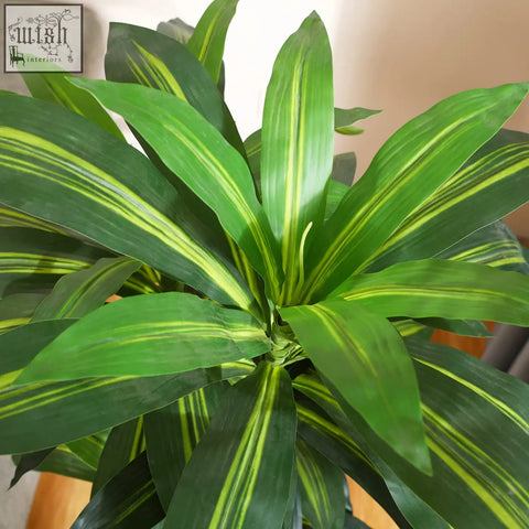 A vibrant green artificial dracaena tree with yellow-striped broad leaves in a decorative indoor pot for home or office