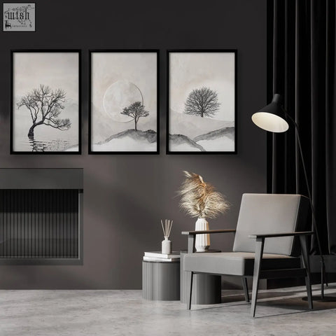 Gray armchair with sleek wooden arms next to forest art scandinavian trees and moon landscape wall art prints set of 3