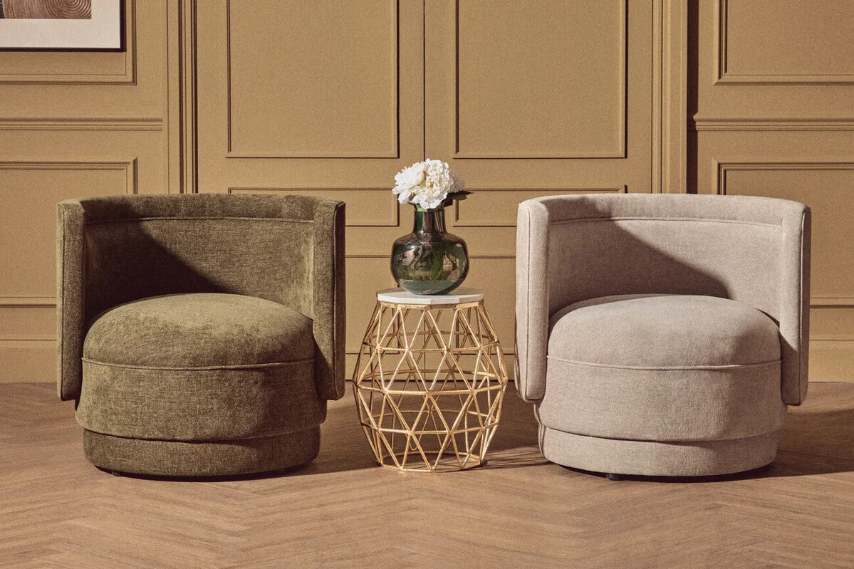 Two forest green chenille effect accent chairs with curved cushioned seats on herringbone wood floor