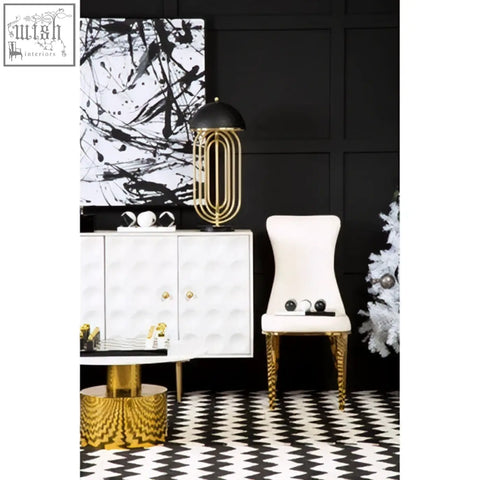 Forli white dining chair with gold finish stainless steel legs and a gold-toned paperclip-shaped lamp with black shade