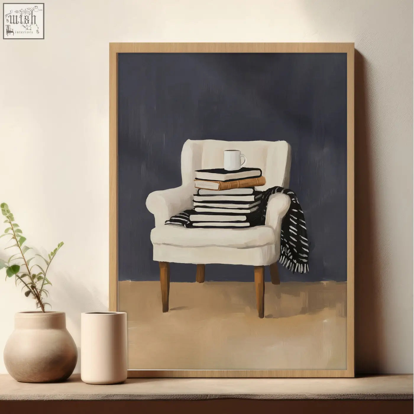 Framed piece wall art showing a white upholstered armchair with wooden legs, books, and a striped blanket for a cozy reading nook