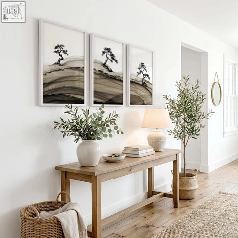 White ceramic vase with green eucalyptus branches beside framed asian wall art of japanese ink bonsai pine trees set of 3