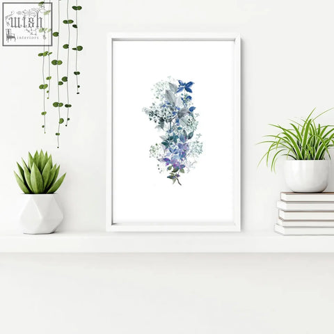 A framed shabby chic wall print with blue and purple floral arrangements and butterflies in a white frame