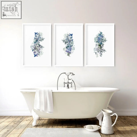 Three shabby chic framed pictures with blue and purple floral wall prints above a white clawfoot bathtub