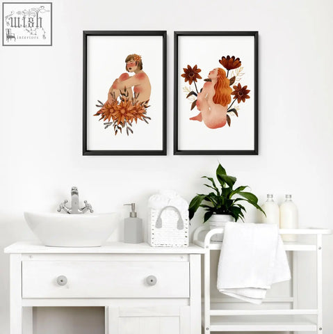 Two framed pictures featuring nude ladies with autumn flowers in sleek black frames perfect for bathroom wall art prints