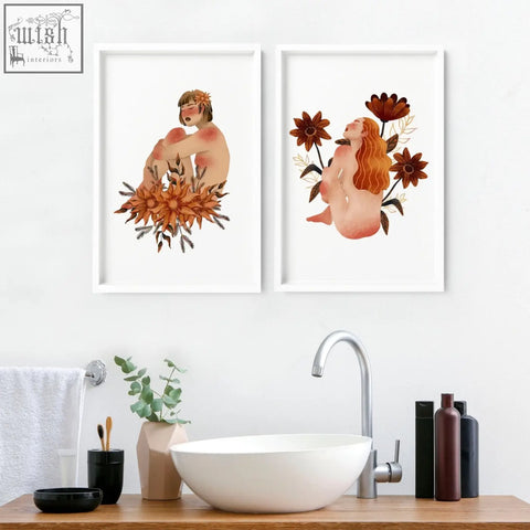 Two framed pictures of nude figures with autumnal flowers in white frames perfect as wall art prints for bathrooms