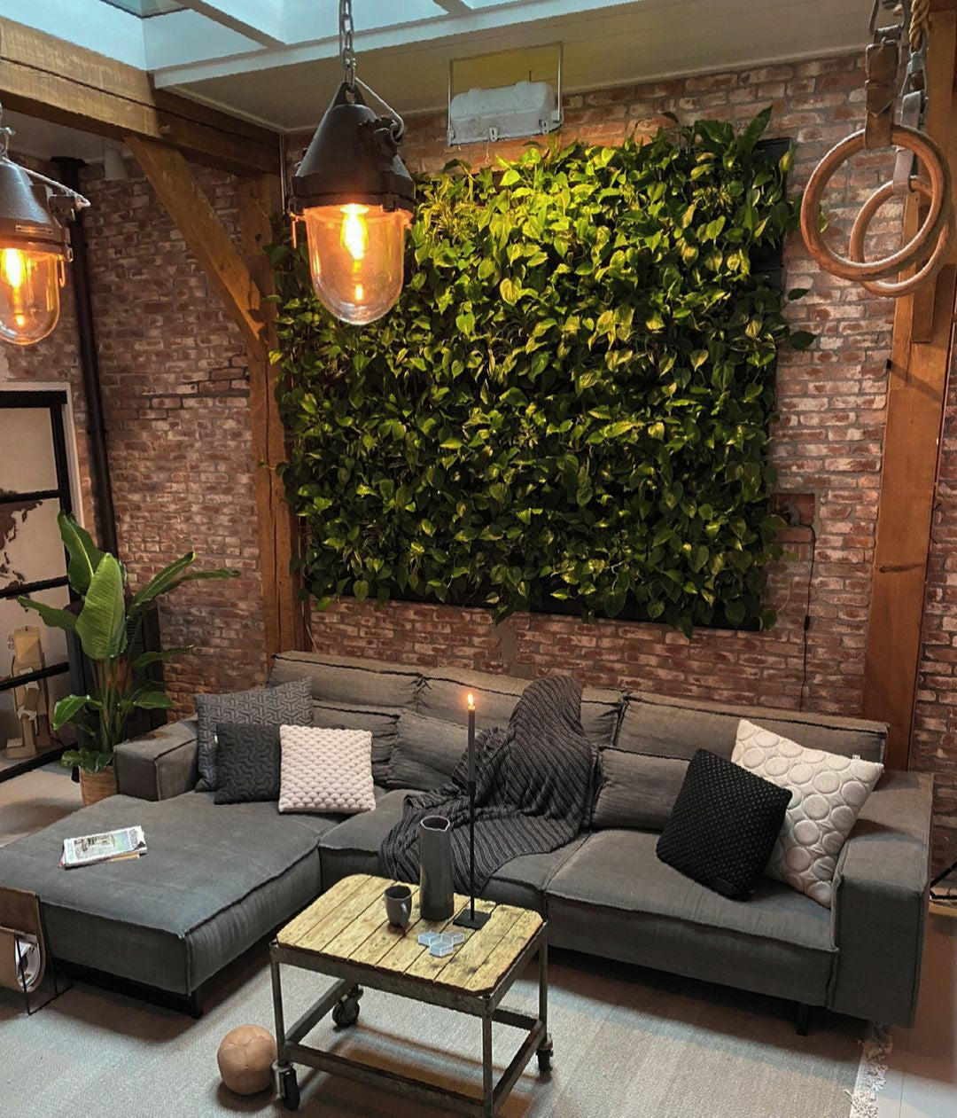 Gray sectional sofa with textured throw pillows and dark gray knit blanket next to frameless living wall cassette table