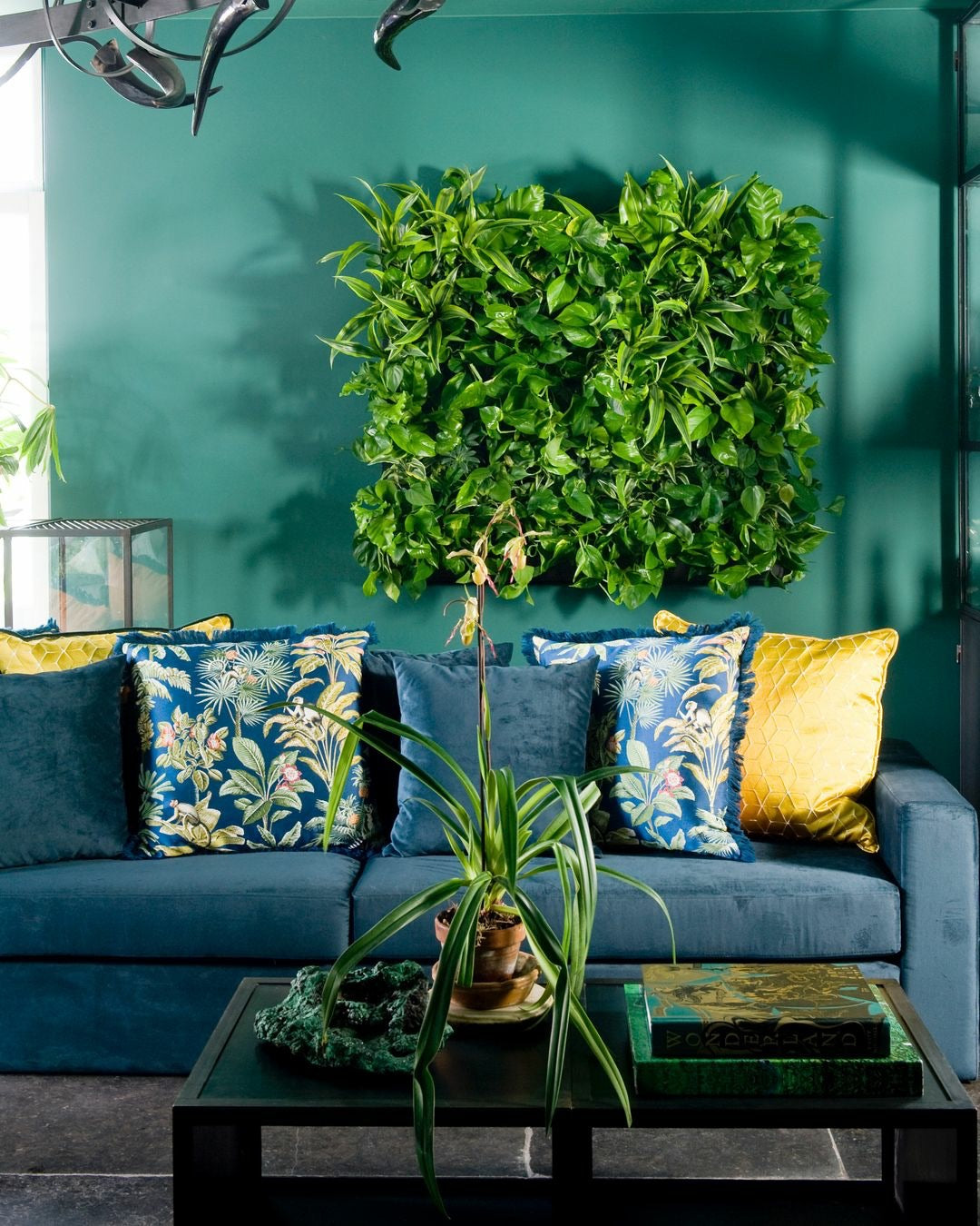 A frameless living wall system with vibrant green foliage on a teal wall featuring a plant cassette table design