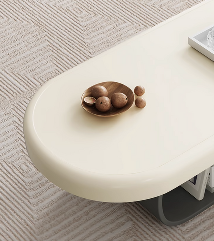 Cream-colored oval freda coffee table with smooth minimalist surface and sleek curved legs in milky white finish
