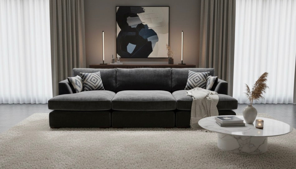 Dark gray fabric freedom sofa double chaise with geometric throw pillows and matching stool with light blanket draped