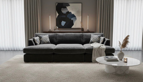 Dark gray fabric freedom sofa double chaise with geometric throw pillows and matching stool with light blanket draped