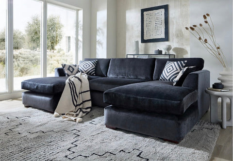 Dark gray velvet freedom sofa double chaise with matching stool and black and white geometric throw pillows