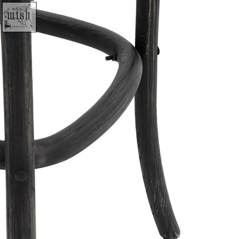 Black wrought iron leg with curved textured design on french bistro bar stool featuring hand woven rattan seat